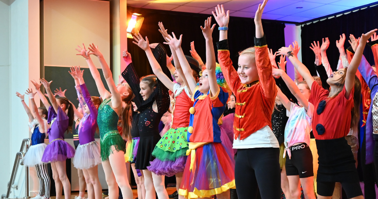 Children performing on stage in costumes