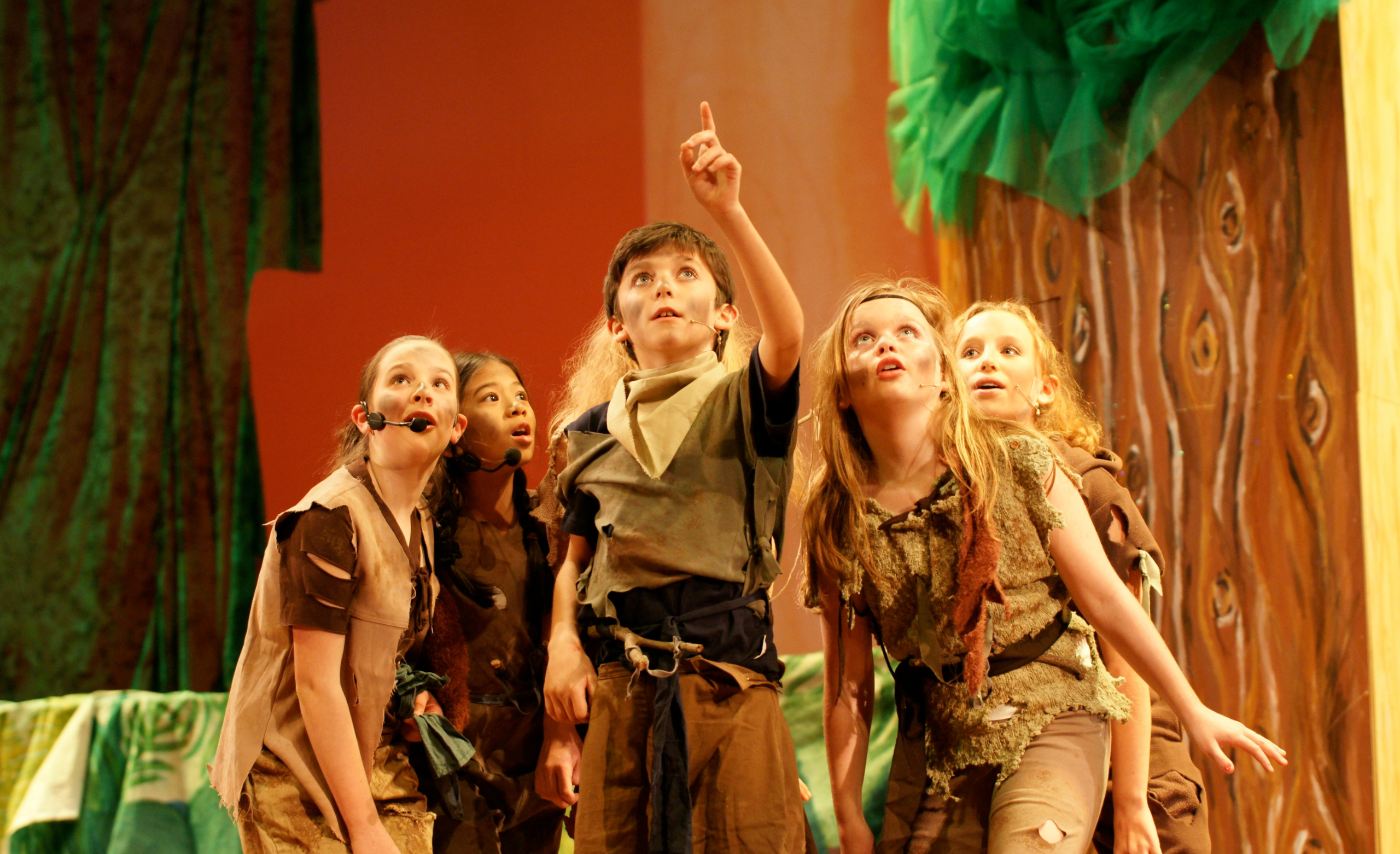 Children performing onstage in brown clothing